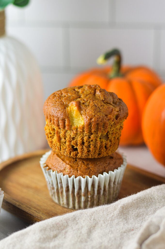 A stack of Apple Pumpkin Muffins with some mini pumpkins in the background.