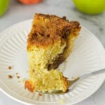 Easy Apple Coffee Cake on a small white plate with a forkful taken out, showing its fluffy texture.