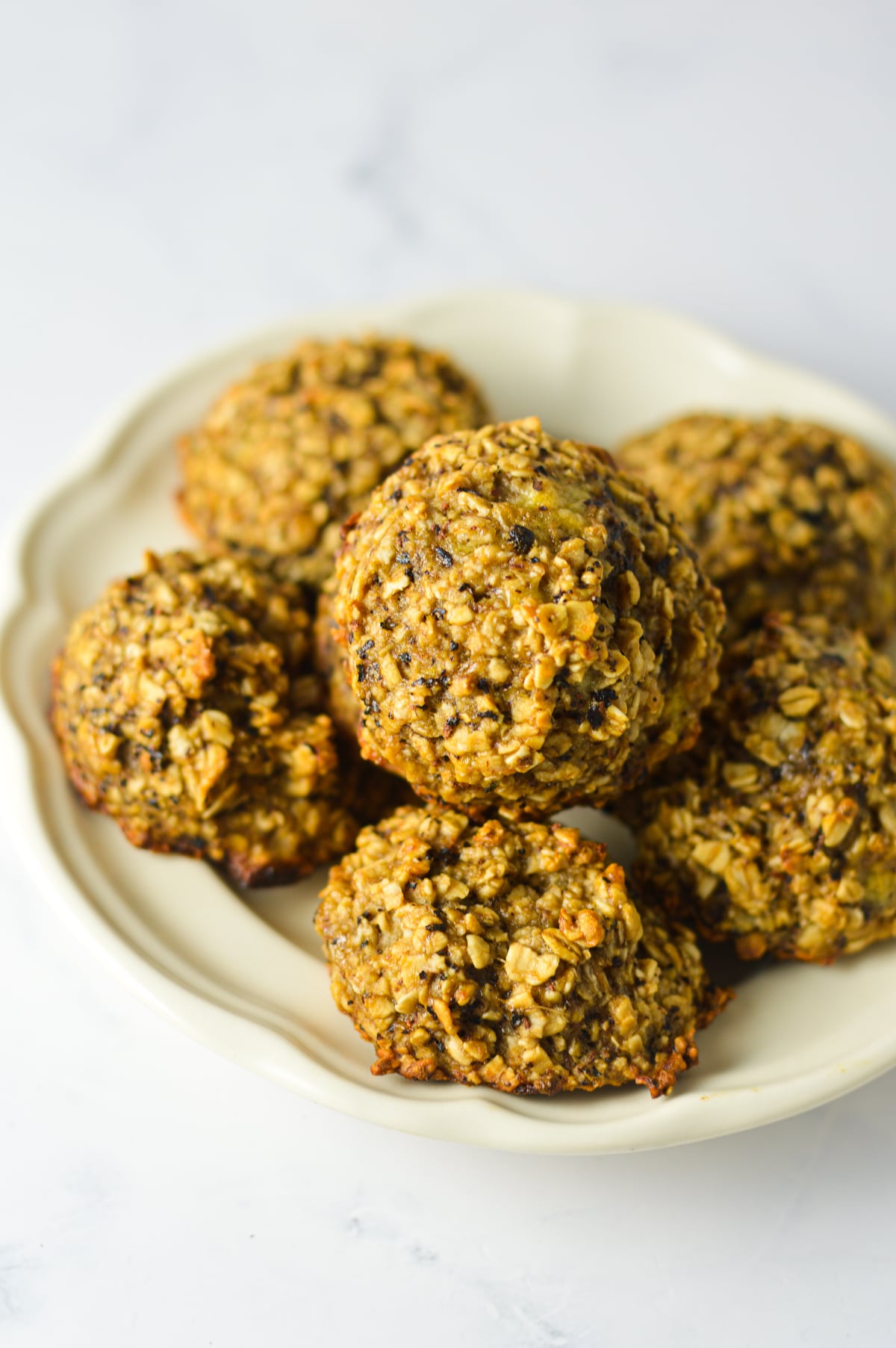 Freshly baked golden-brown eggless banana chai latte cookies on a small white plate.