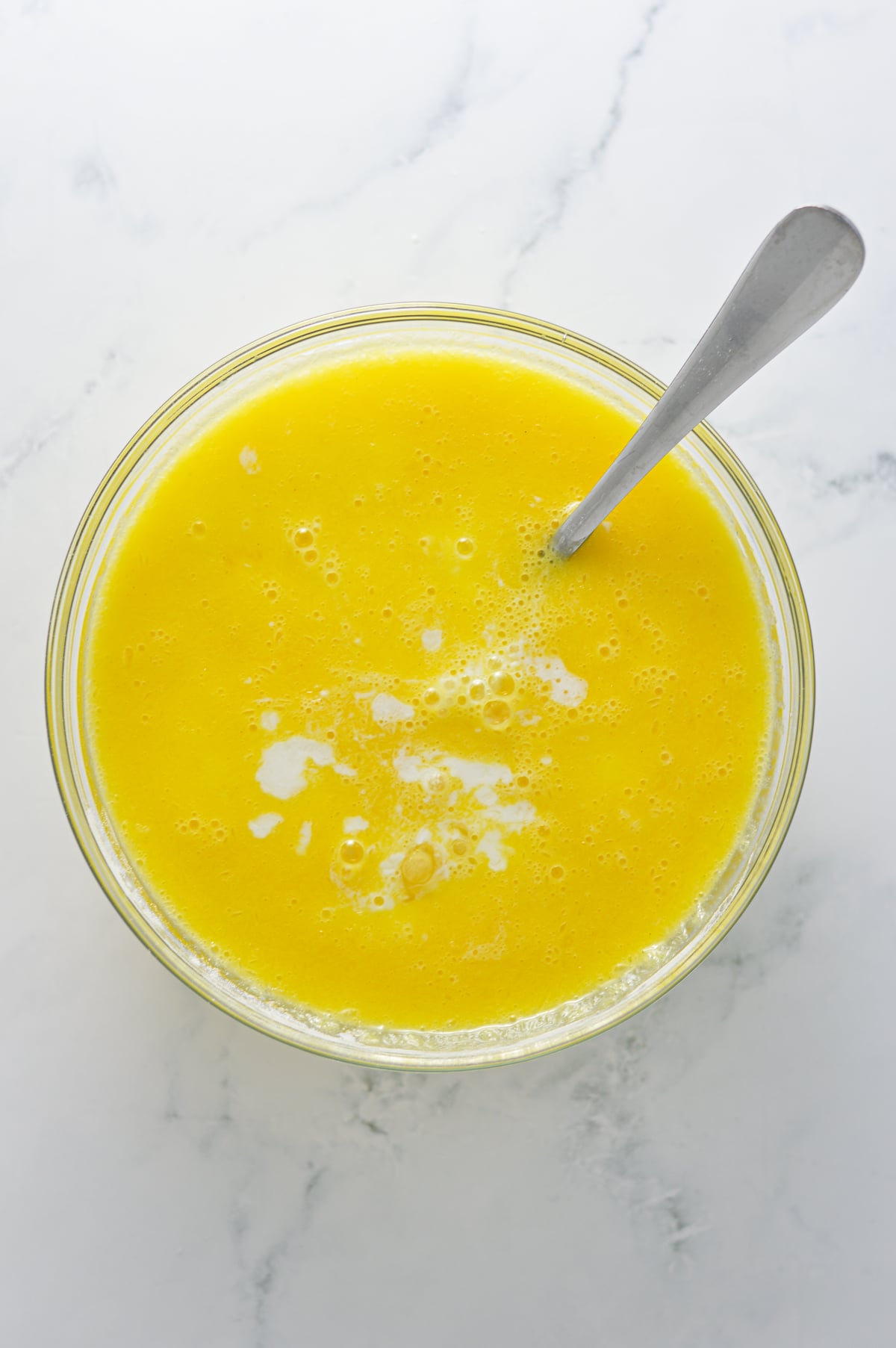 A small glass bowl filled with the eggs, melted butter and the soured milk.