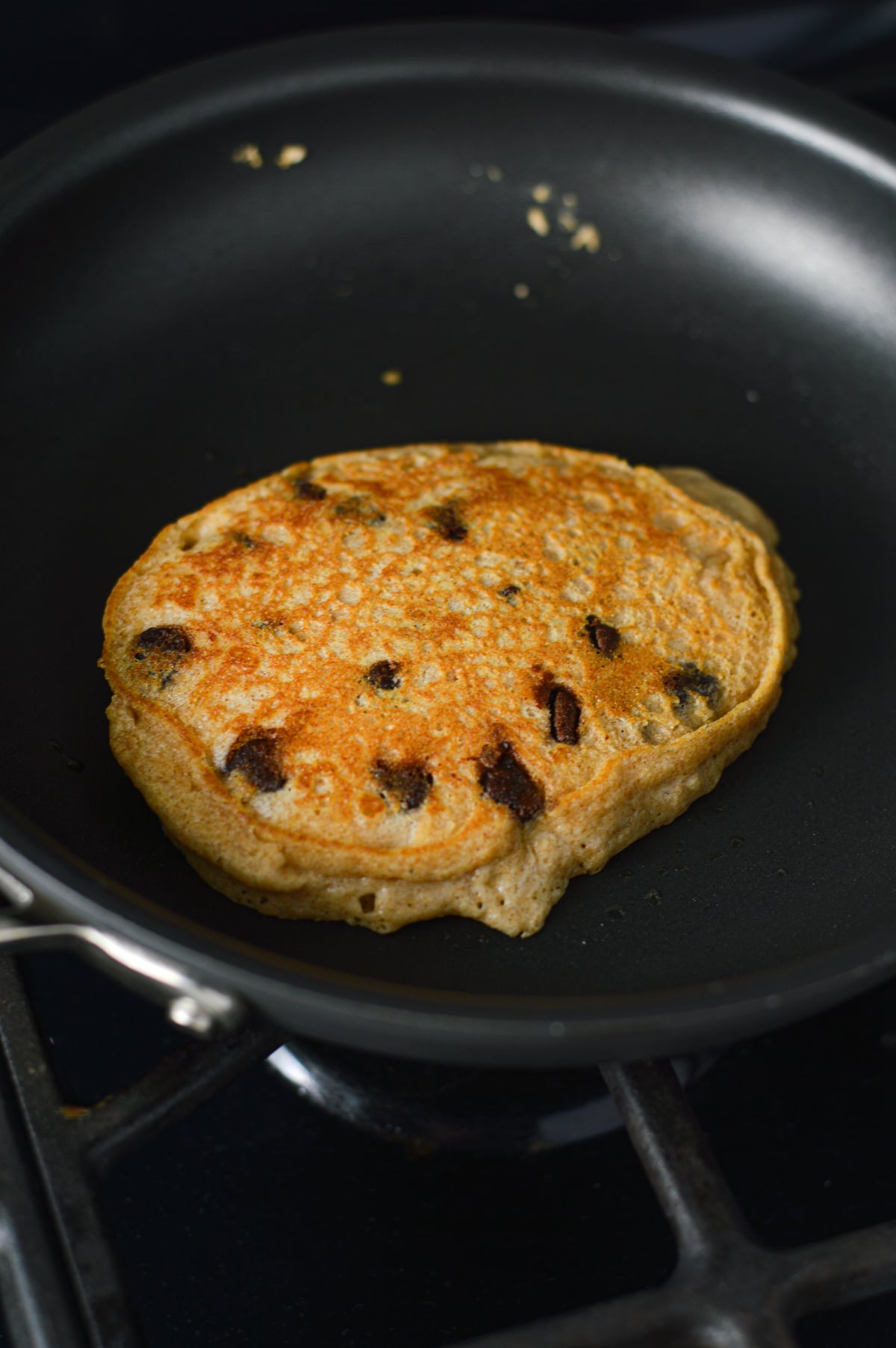 A Whole Wheat Chocolate Chip Pancake being cooked on a small skillet.