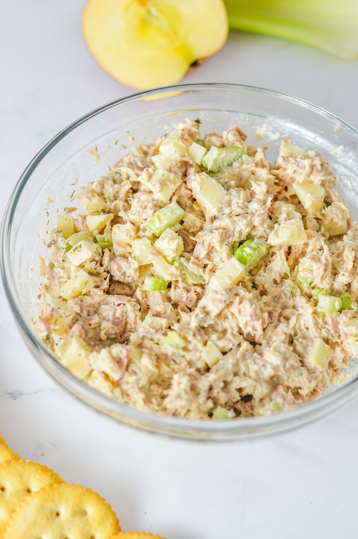 A bowl of apple tuna salad served with ritz crackers on the side.