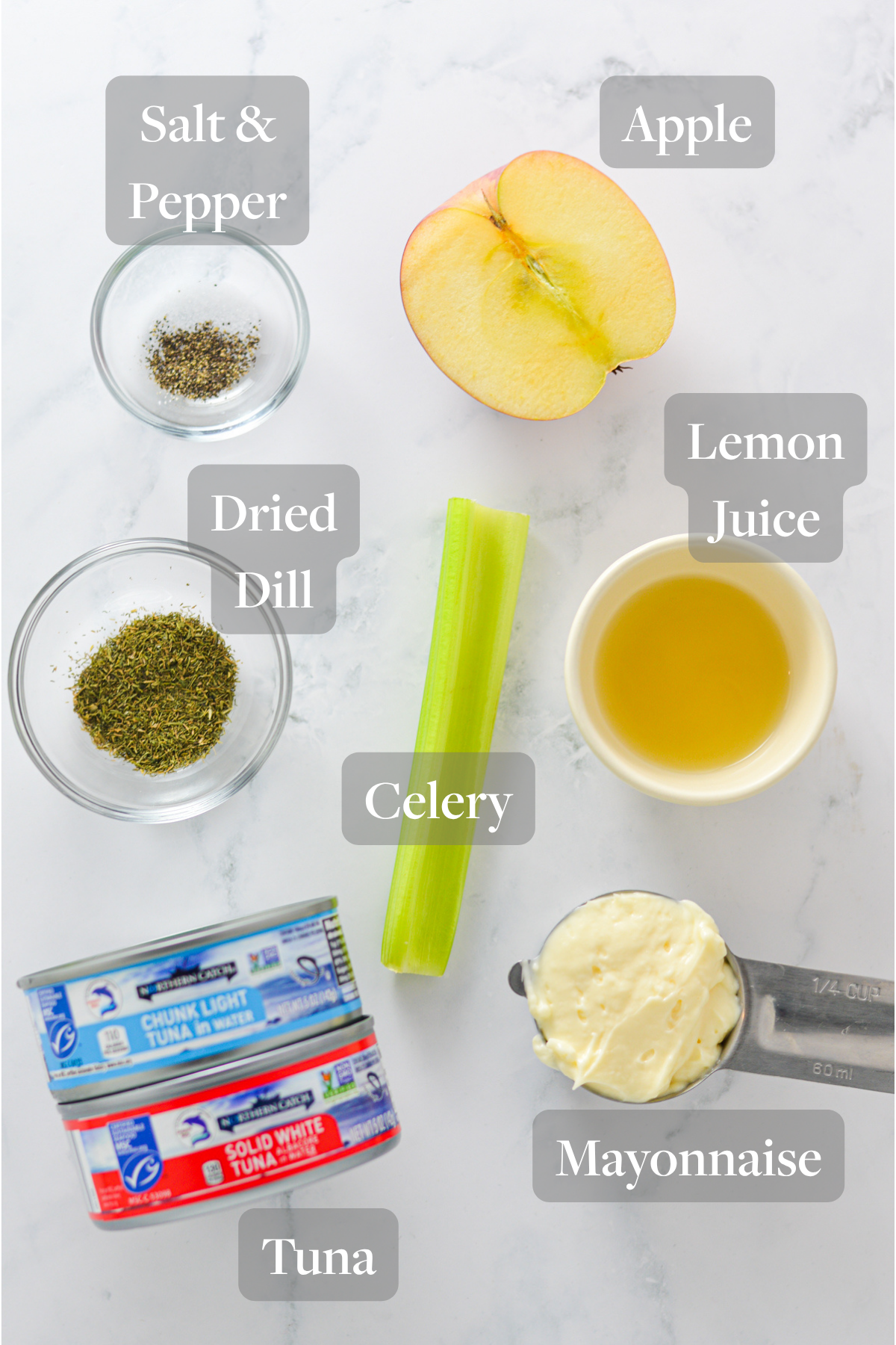 All the ingredients needed to make Apple Tuna Salad laid out on a marble surface.