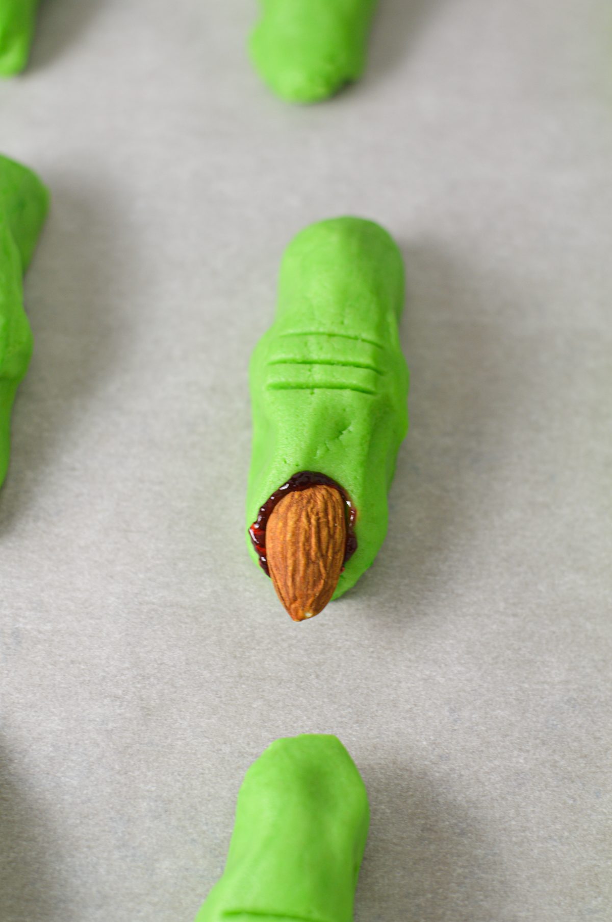 Unbaked witch finger cookies on a cookie sheet lined with parchment paper.