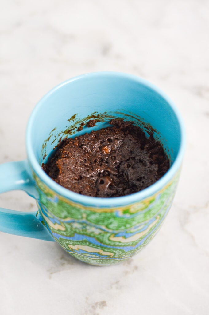 Homemade Banana Nutella Mug Cake in a coffee mug, with a glossy chocolate top to the freshly made cake.