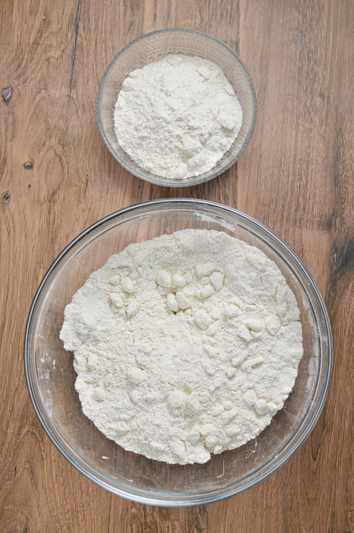 A small bowl and a large bowl filled with the dry ingredients to the butter cake batter, with some lumps of cold butter cut in.