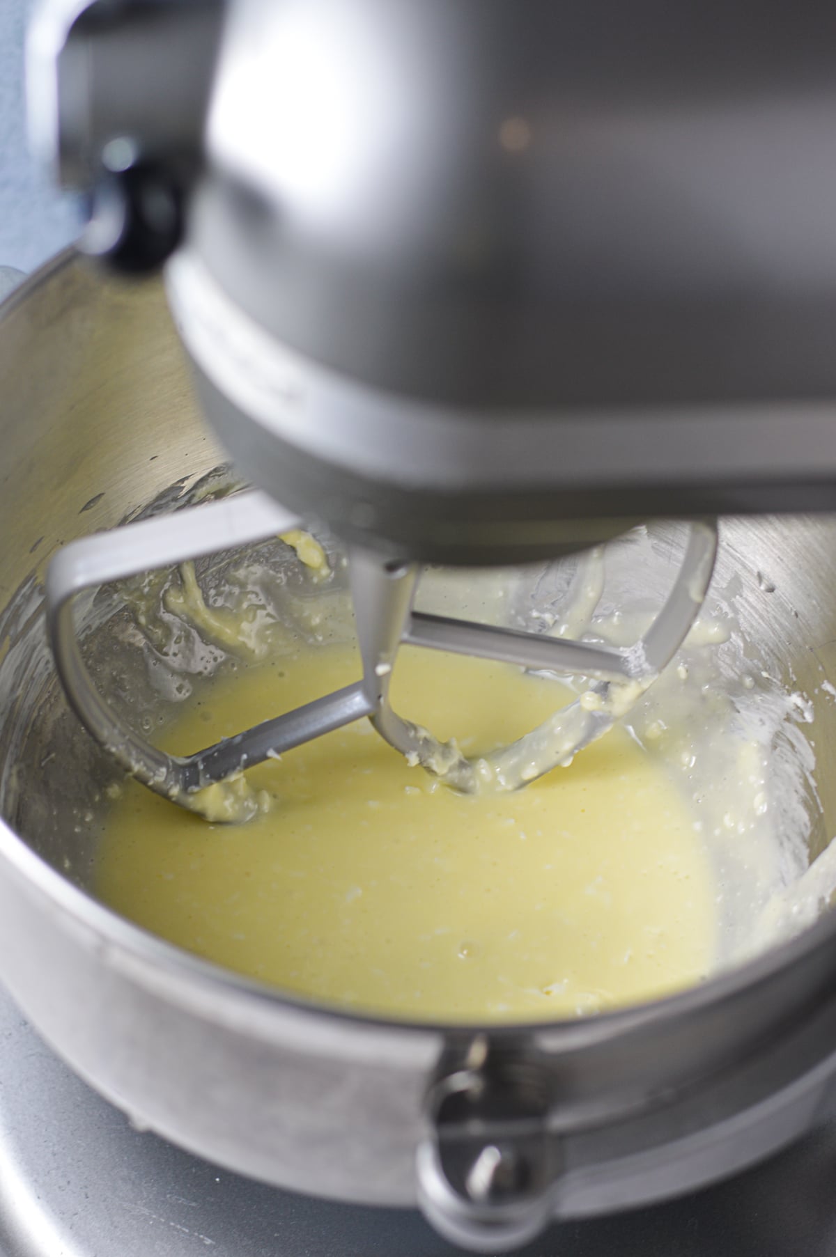 A stand mixer with a paddle attachment mixing the cream cheese filling ingredients together.