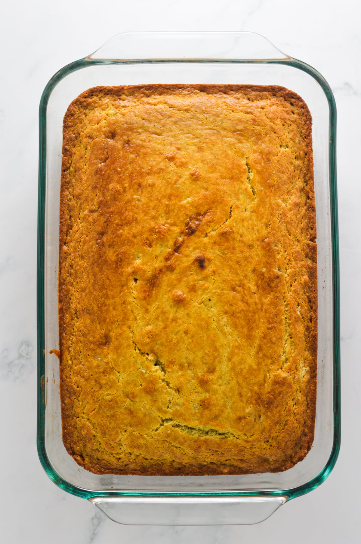A freshly baked golden brown Banana Vanilla Cake in a glass baking pan.