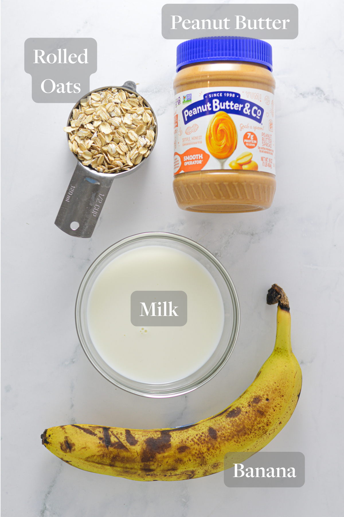 Everything you need to make Peanut Butter Banana Oatmeal laid out on a marble surface.