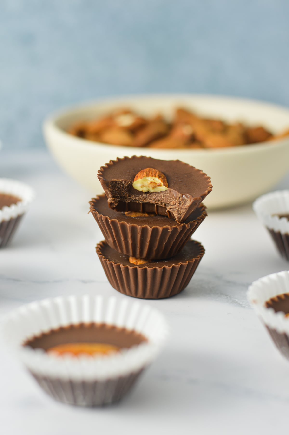 A stack of Almond Mini Nutella Cups with the mini paper liners taken off and a bite taken out of the top chocolate cup, showing the rich texture.