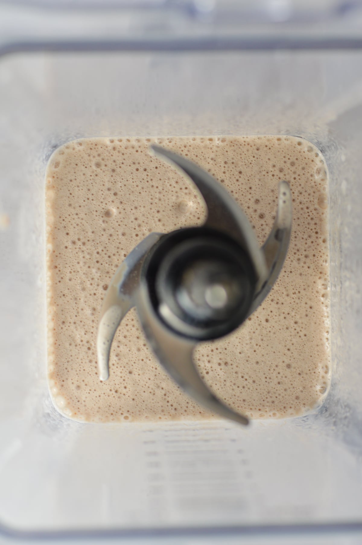 Top-down view inside a blender pitcher containing a freshly blended creamy chocolate milk tea mixture over the blades.