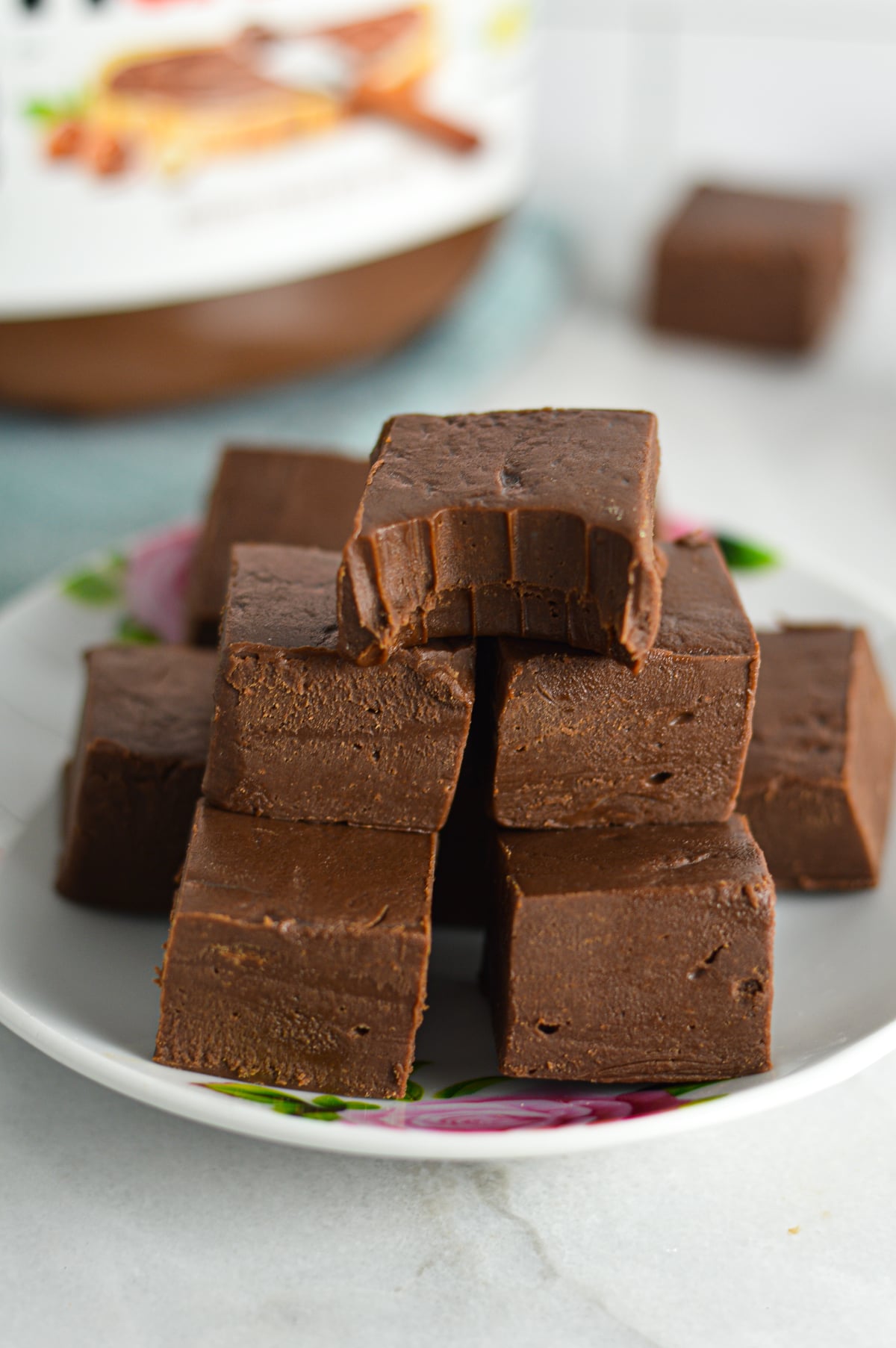 A tall, close-up stack of rich, sliced squares of chocolate Nutella fudge resting on a white plate.