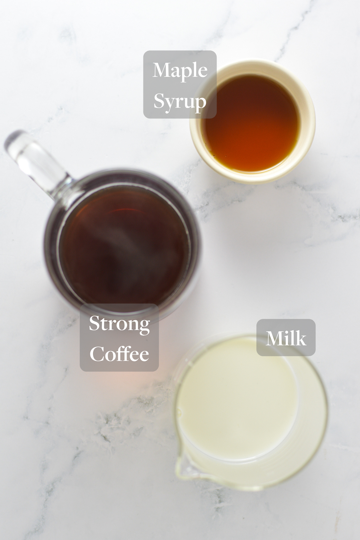 All the ingredients you need to make a mug of Maple Latte laid out on a marble countertop.