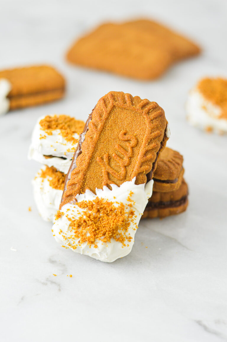 Nutella Biscoff Sandwiches on a granite surface. The Lotus Biscoff Cookie sandwiches are dipped in white chocolate and sprinkled with crushed biscoff cookies.