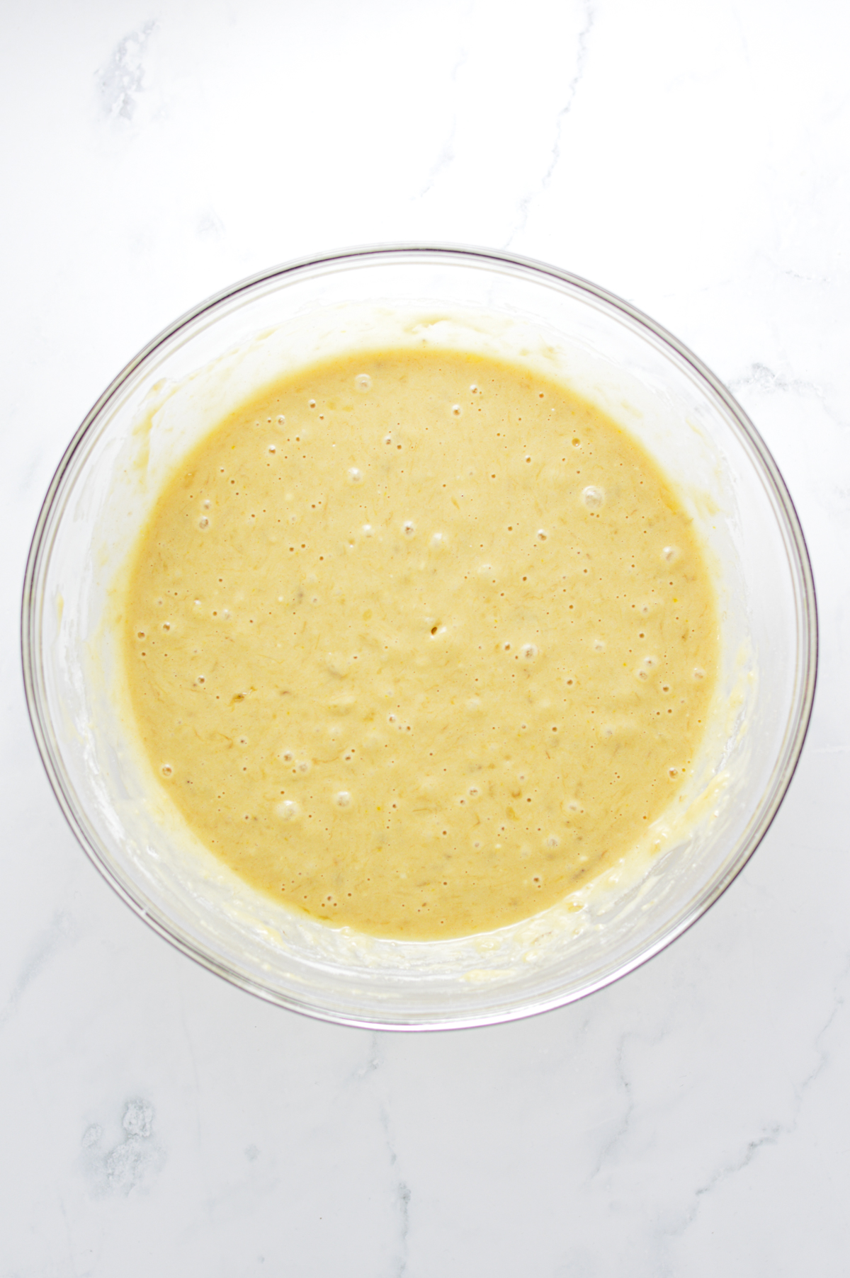 The batter for the Cinnamon Sugar Banana Bread Donuts in a large glass bowl.