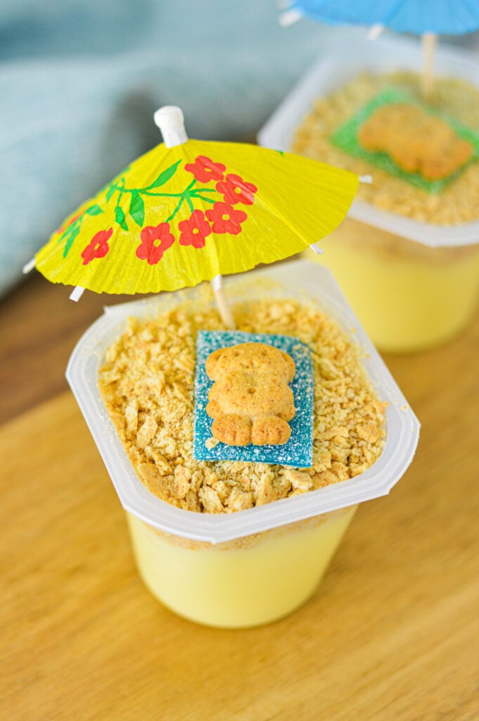 Sand Pudding Cups in a disposable pudding cup with a layer of graham cracker crumbs resembling sand.