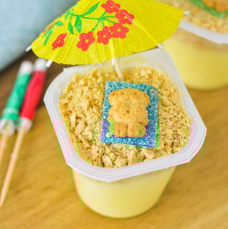 Sand Pudding Cups with a teddy graham on top of a sour strip candy resembling a beach scene.