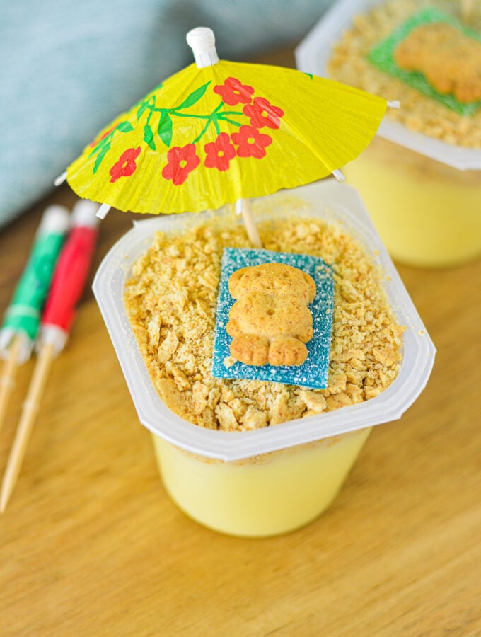 Sand Pudding Cups with a teddy graham on top of a sour strip candy resembling a beach scene.
