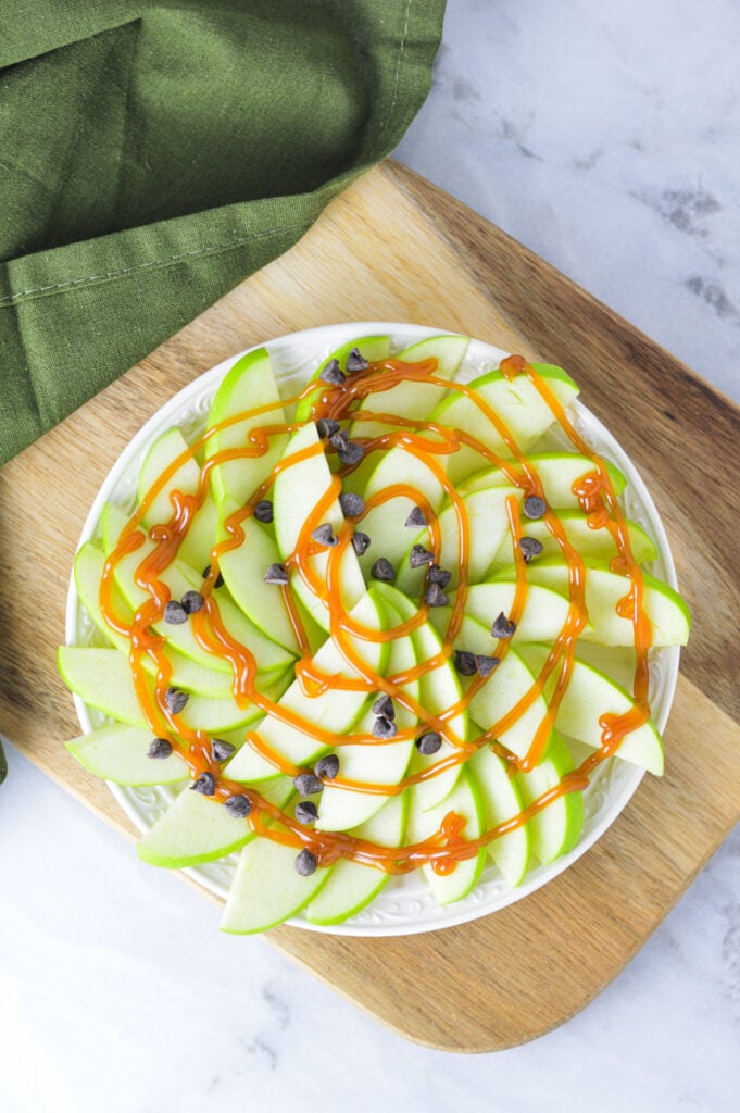 A small bowl of Apple Nachos for One on a wooden cutting board.