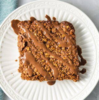 A Nutella Oatmeal Breakfast Bar on a white plate with Nutella drizzled on top.