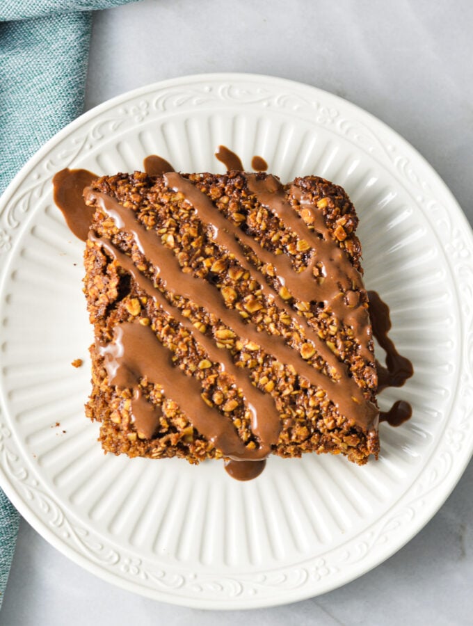 A Nutella Oatmeal Breakfast Bar on a white plate with Nutella drizzled on top.