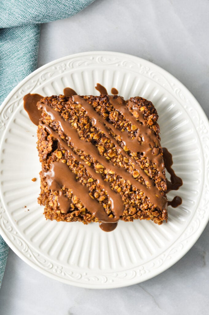 A Nutella Oatmeal Breakfast Bar on a white plate with Nutella drizzled on top.