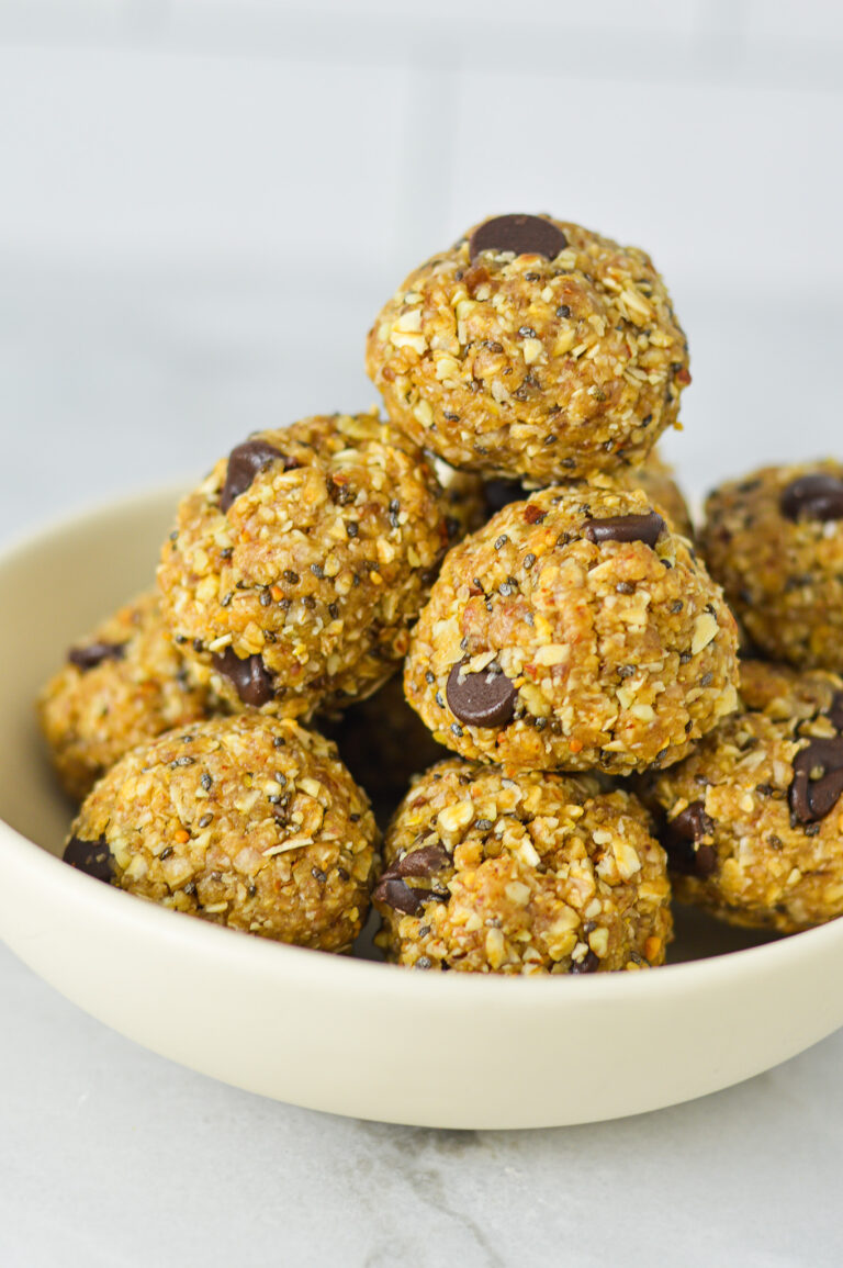A small shallow bowl filled with Almond Peanut Butter Chocolate Energy Bites, showing its hearty texture filled with chia seeds, chocolate chips and rolled oats.