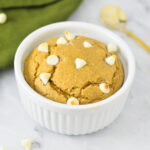 A small ramekin of White Chocolate Protein Blended Baked Oats with a small golden spoon in the background.