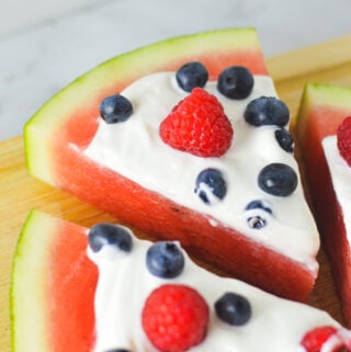 Sliced Healthy Watermelon Pizza, topped with fresh raspberries, blueberries and Greek yogurt.