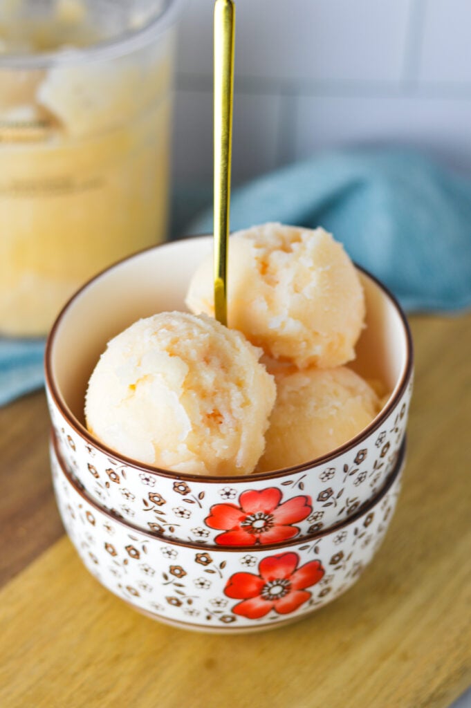 A bowl of refreshing Ninja Creami Grapefruit Italian Ice wit a small spoon sticking out.