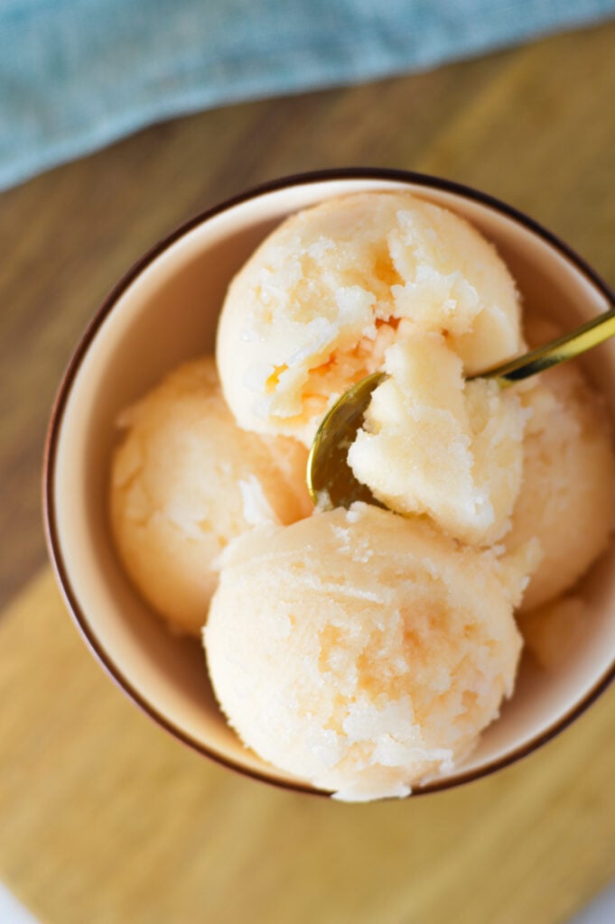 A spoon inside a bowl of Ninja Creami Grapefruit Italian Ice, showing the refreshing texture.