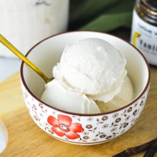 A bowl full of Ninja Creami Vanilla Bean Ice Cream, with a gold spoon sticking out of the bowl.