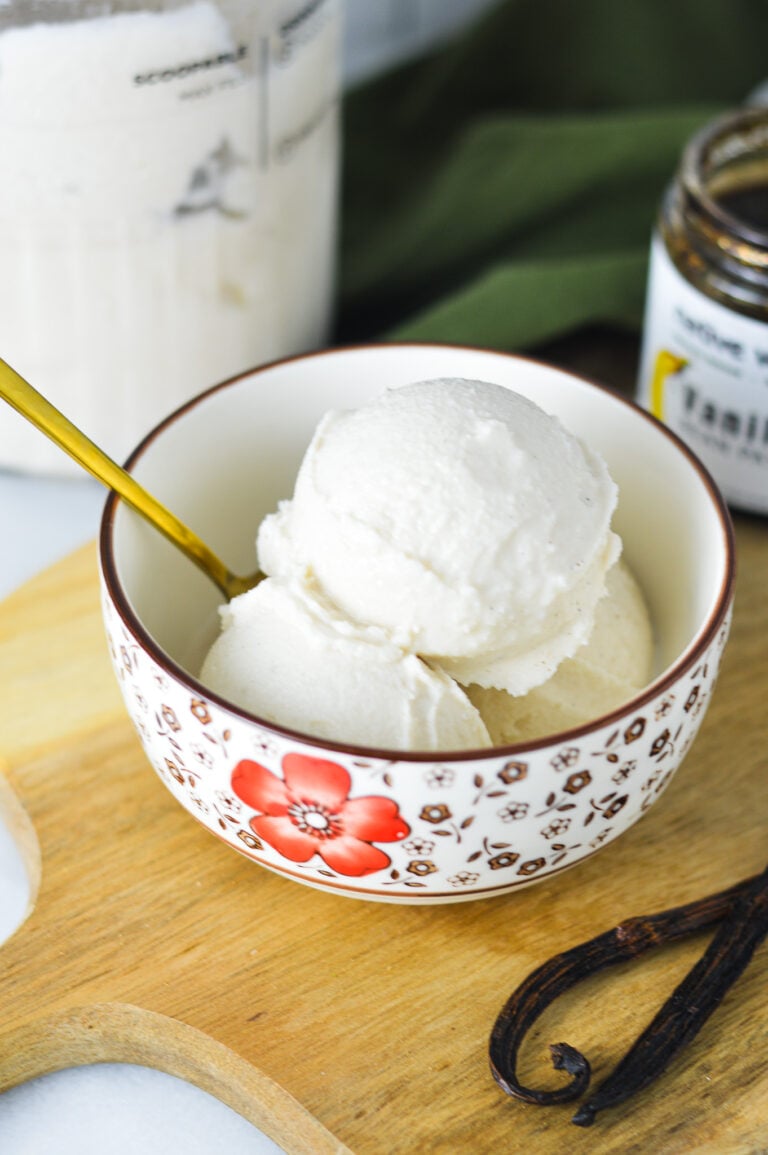 A bowl full of Ninja Creami Vanilla Bean Ice Cream, with a gold spoon sticking out of the bowl.
