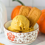 A bowl of creamy Ninja Creami Vegan Pumpkin Biscoff Protein Ice Cream with some Lotus Biscoff cookies sticking out.