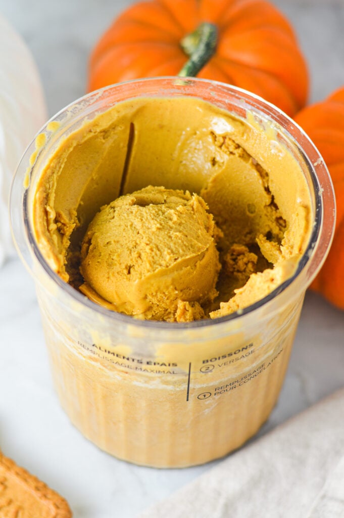A Ninja Creami container filled with Ninja Creami Vegan Pumpkin Biscoff Protein Ice Cream, with a scoop showing its creamy texture.