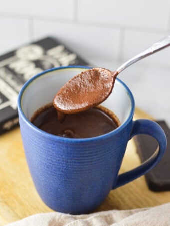 A spoon scooping some Rich Hot Chocolate from a blue mug.