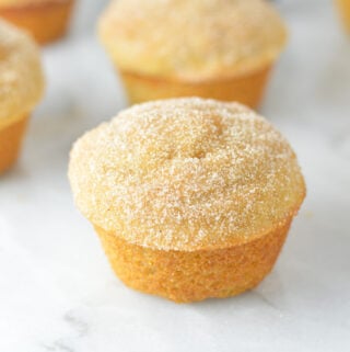 A batch of cake-like Donut Muffins arranged neatly on a granite surface.