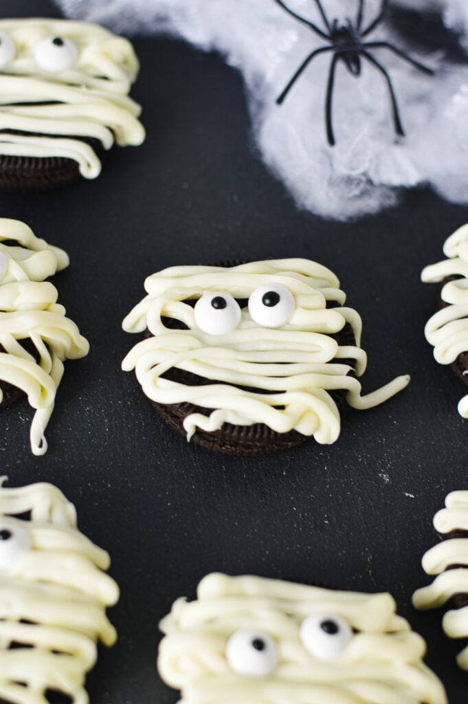 Some Oreos decorated to look like mummies with melted white chocolate drizzled on top and candy eyeballs.