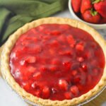 A homemade Strawberry Pie with chunks of strawberry in the glossy filling inside the golden brown flaky crust.