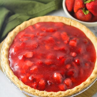 A homemade Strawberry Pie with chunks of strawberry in the glossy filling inside the golden brown flaky crust.