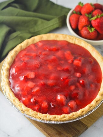A homemade Strawberry Pie with chunks of strawberry in the glossy filling inside the golden brown flaky crust.