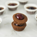 A stack of Cherry Nutella Cups on a granite surface, with more creamy Nutella cups in the background.