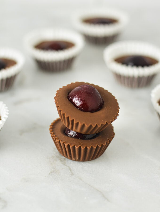 A stack of Cherry Nutella Cups on a granite surface, with more creamy Nutella cups in the background.