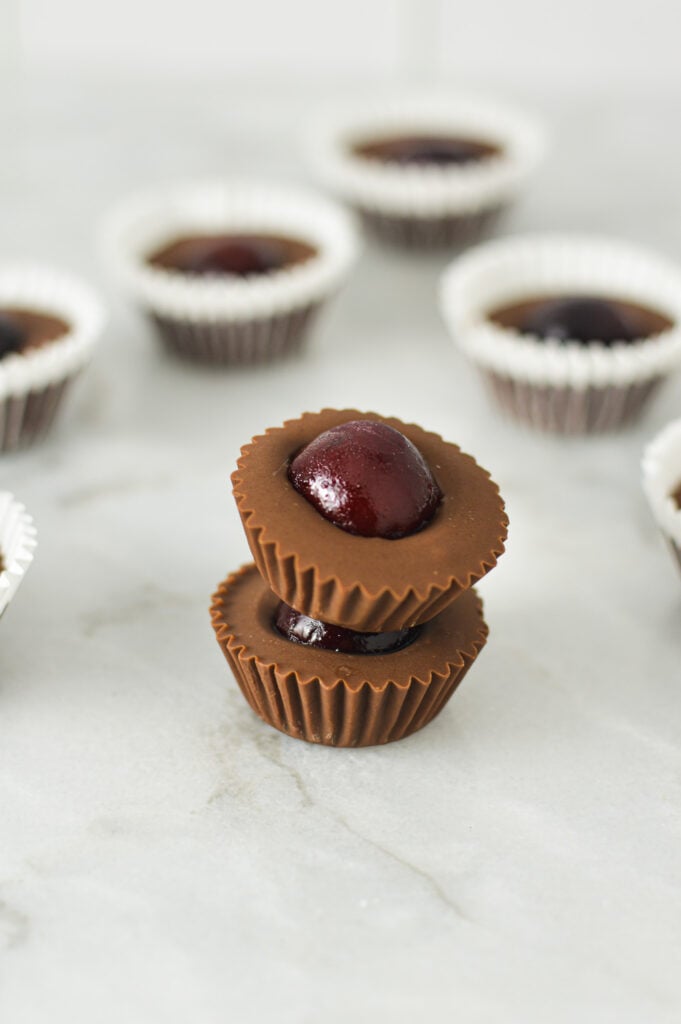 A stack of Cherry Nutella Cups on a granite surface, with more creamy Nutella cups in the background.