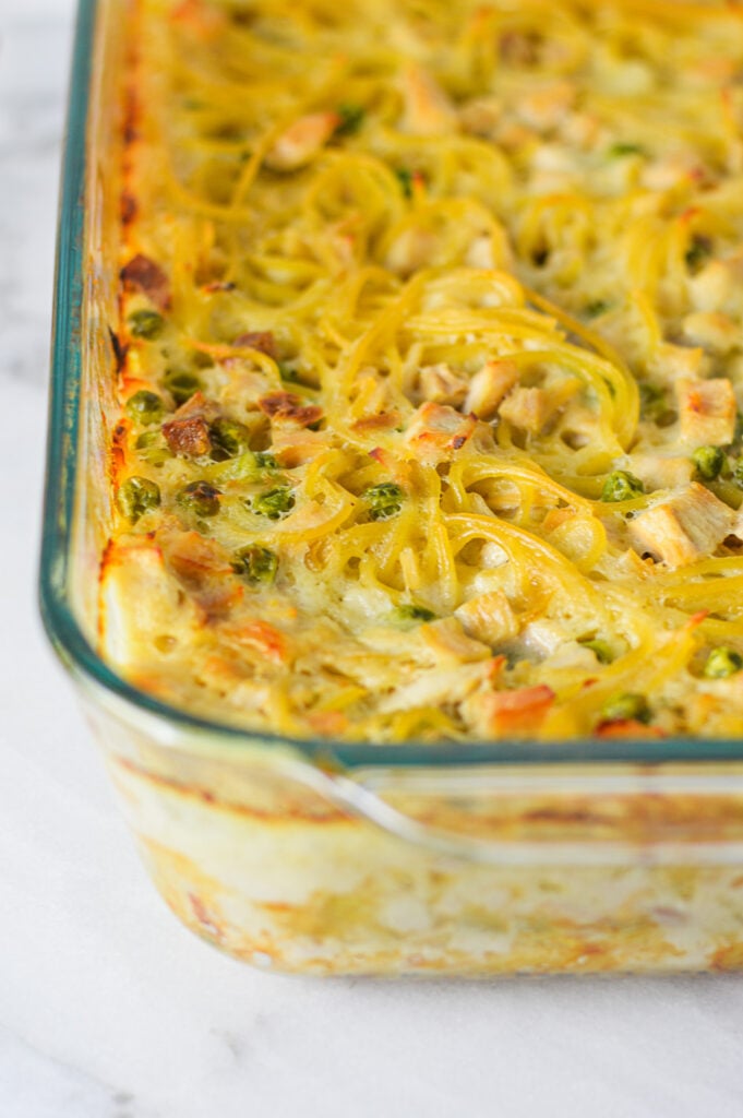 A freshly baked Leftover Turkey Tetrazzini, with cooked spaghetti, chunks of turkey and peas mixed into the creamy dish.
