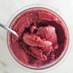 Creamy Ninja Creami Blueberry Watermelon Sorbet with a spoon inside the full pint showing the smooth texture.