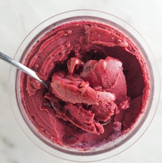 Creamy Ninja Creami Blueberry Watermelon Sorbet with a spoon inside the full pint showing the smooth texture.