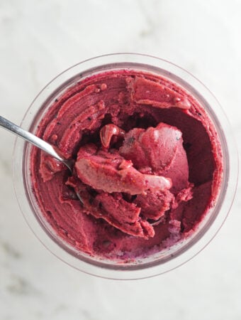 Creamy Ninja Creami Blueberry Watermelon Sorbet with a spoon inside the full pint showing the smooth texture.