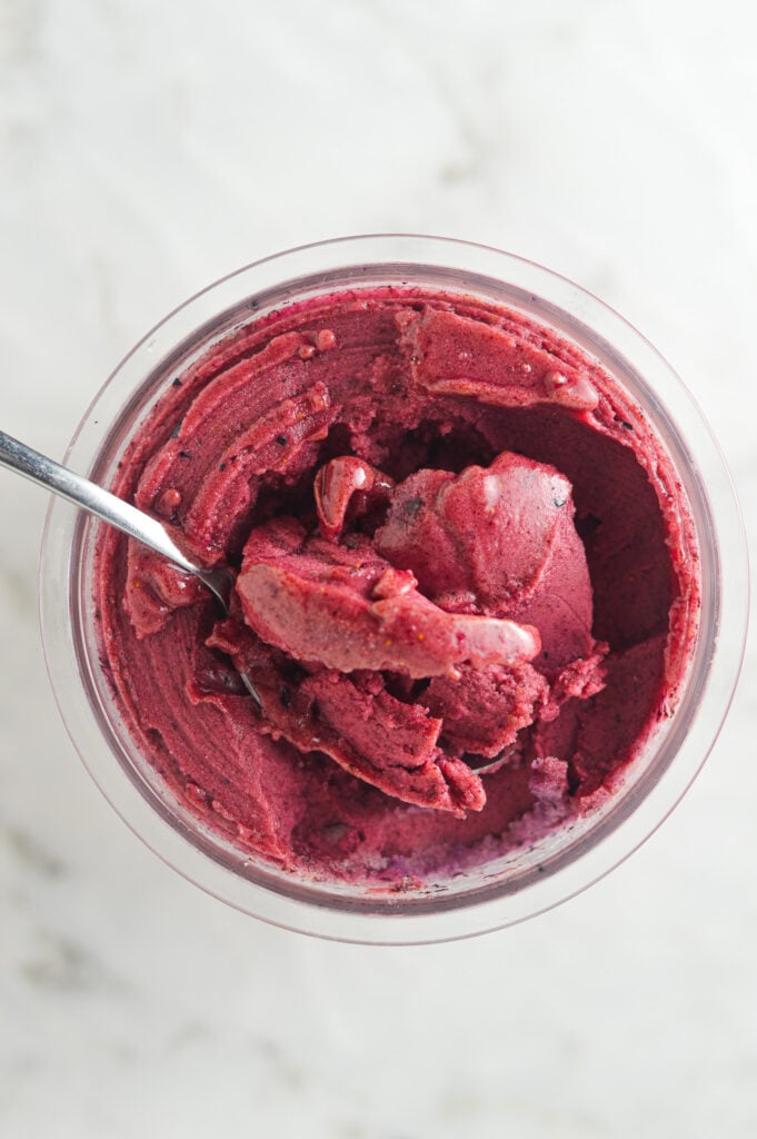 Creamy Ninja Creami Blueberry Watermelon Sorbet with a spoon inside the full pint showing the smooth texture.