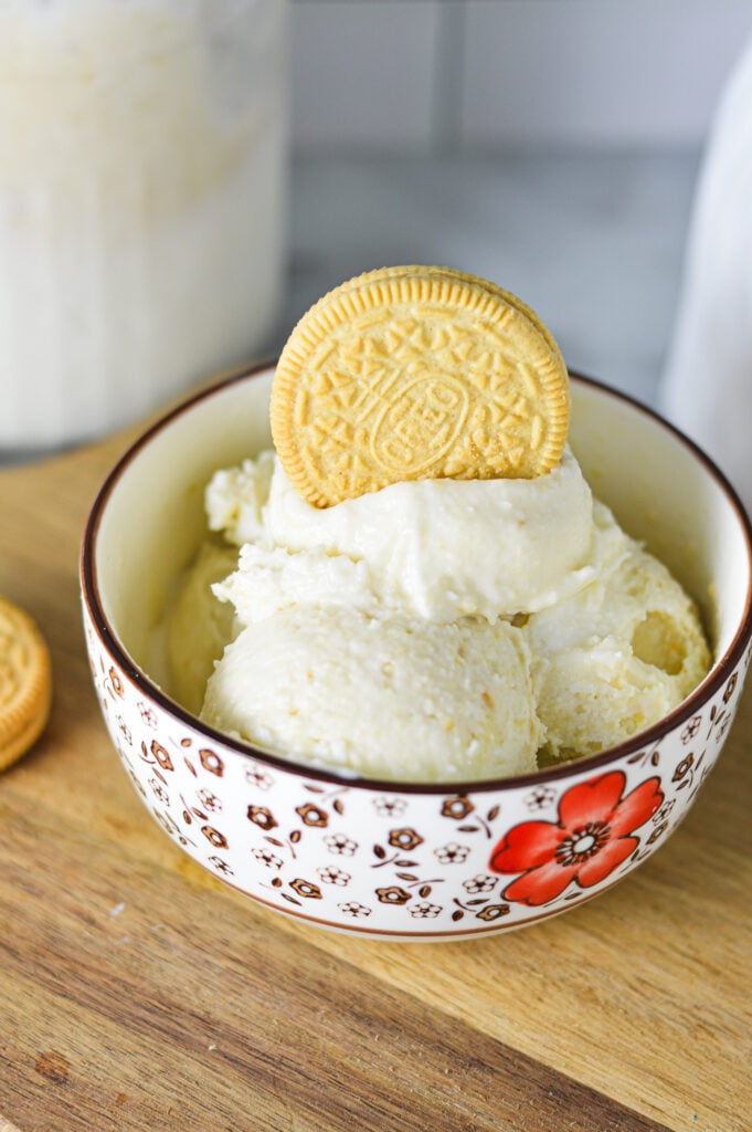 A creamy bowl of Ninja Creami Golden Oreo Ice Cream with a whole Golden Oreo stuck in the ice cream.